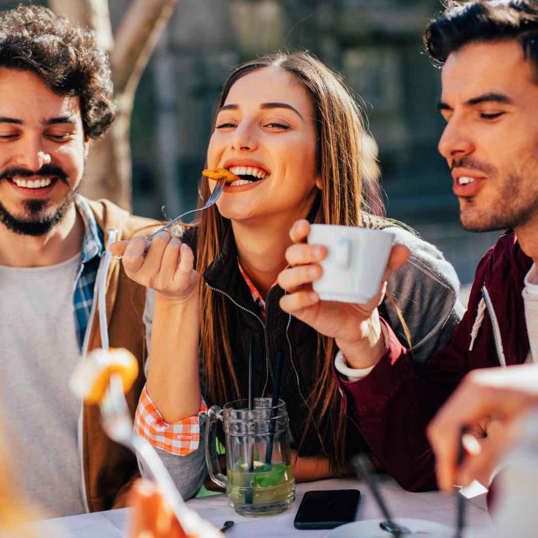 three people eating at a campfire